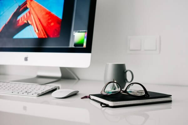 computer-on-table-with-mug-eyeglasses-and-diary-on-table