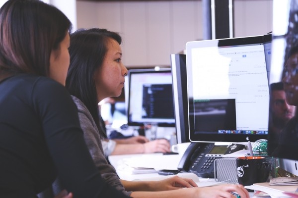 female-colleagues-working-on-computer-sitting-at-office-desk